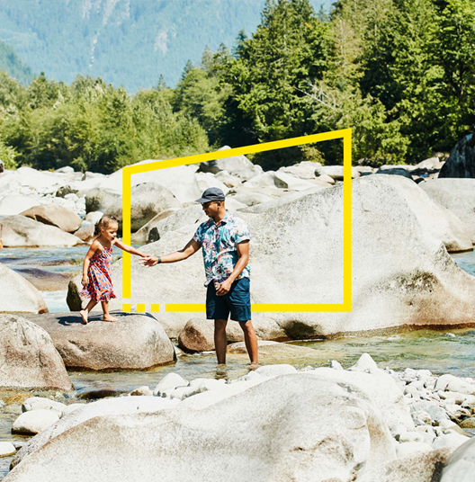 Father-holding-daughters-hand-while-exploring-rocks-in-river