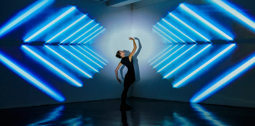 ey-girl-dancing-in-a-studio-with-graphic-patterns-projected-onto-wall-behind-her-510.253.png