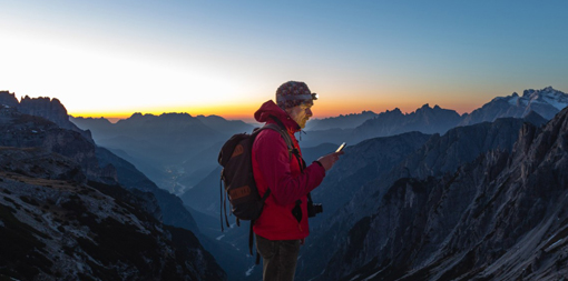 ey-hiker-looking-map-on-mobile-device-mountains-sunset