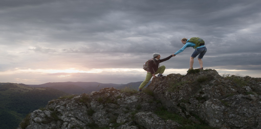 ey-hiker-woman-helping-her-friend-reach-the-top-of-the-mountain