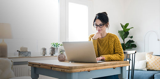 ey-woman-sitting-at-table-using-laptop